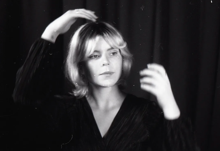 Adelaide singer-songwriter Ella Ion adjusting her hair against a dark backdrop in a grainy black-and-white promotional artist portrait photo.